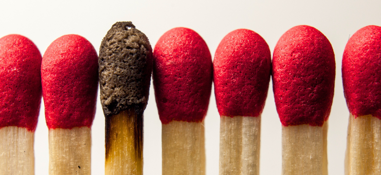 Burnt out matchstick next to unlit matches